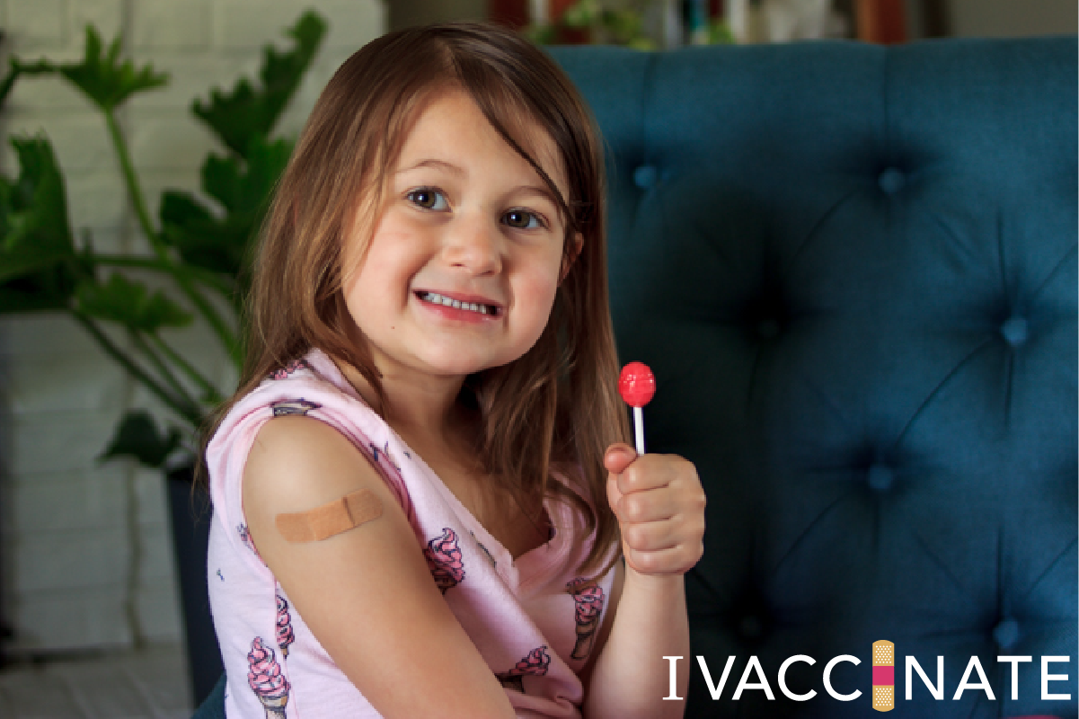 Young girl with bandaid on arm and lollipop