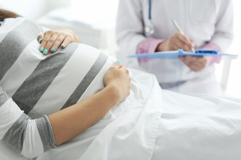 Pregnant woman laying down and talking to doctor