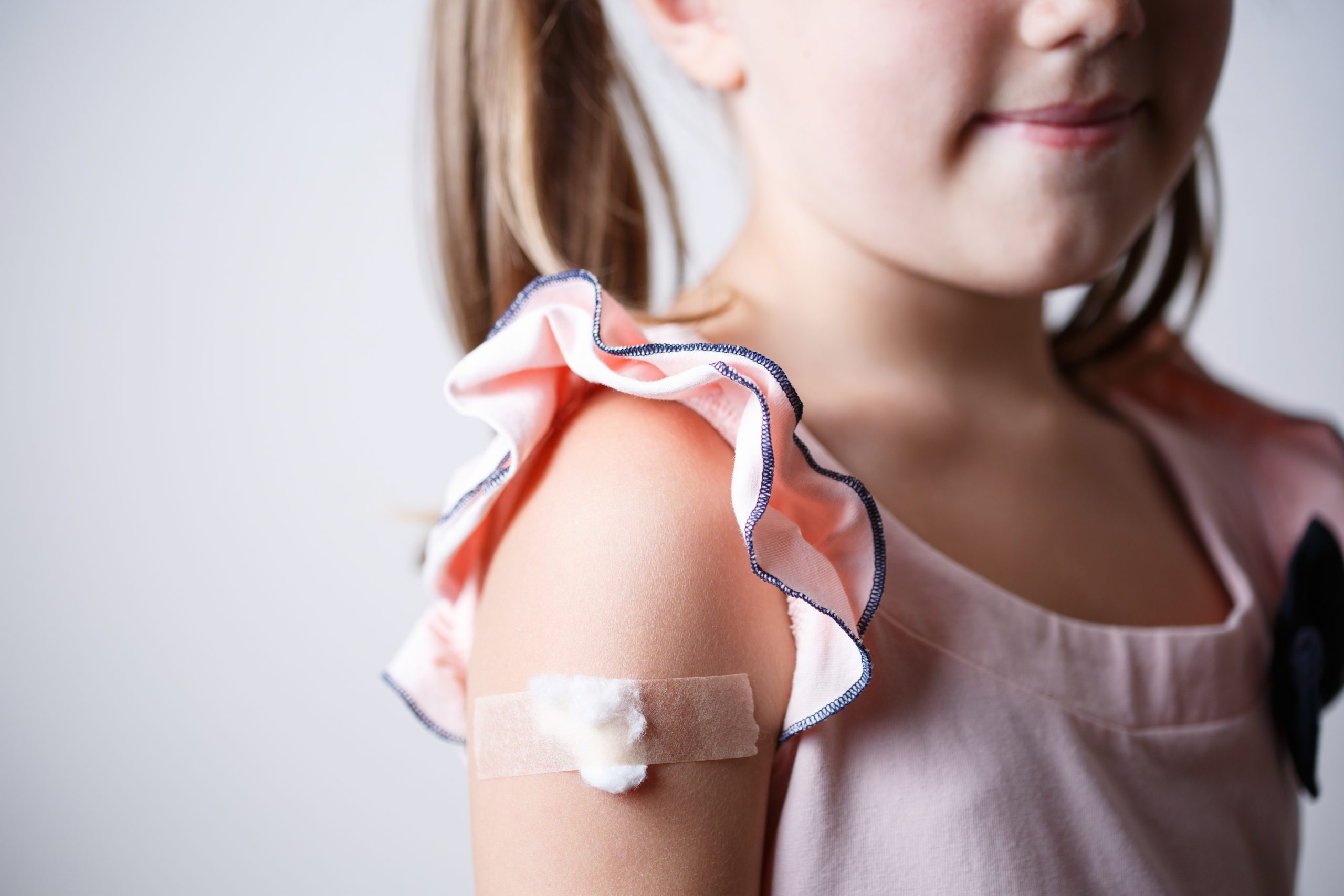 little girl with plaster on the shoulder from the injection, vaccinated in the shoulder, child vaccination, treatment of children patch