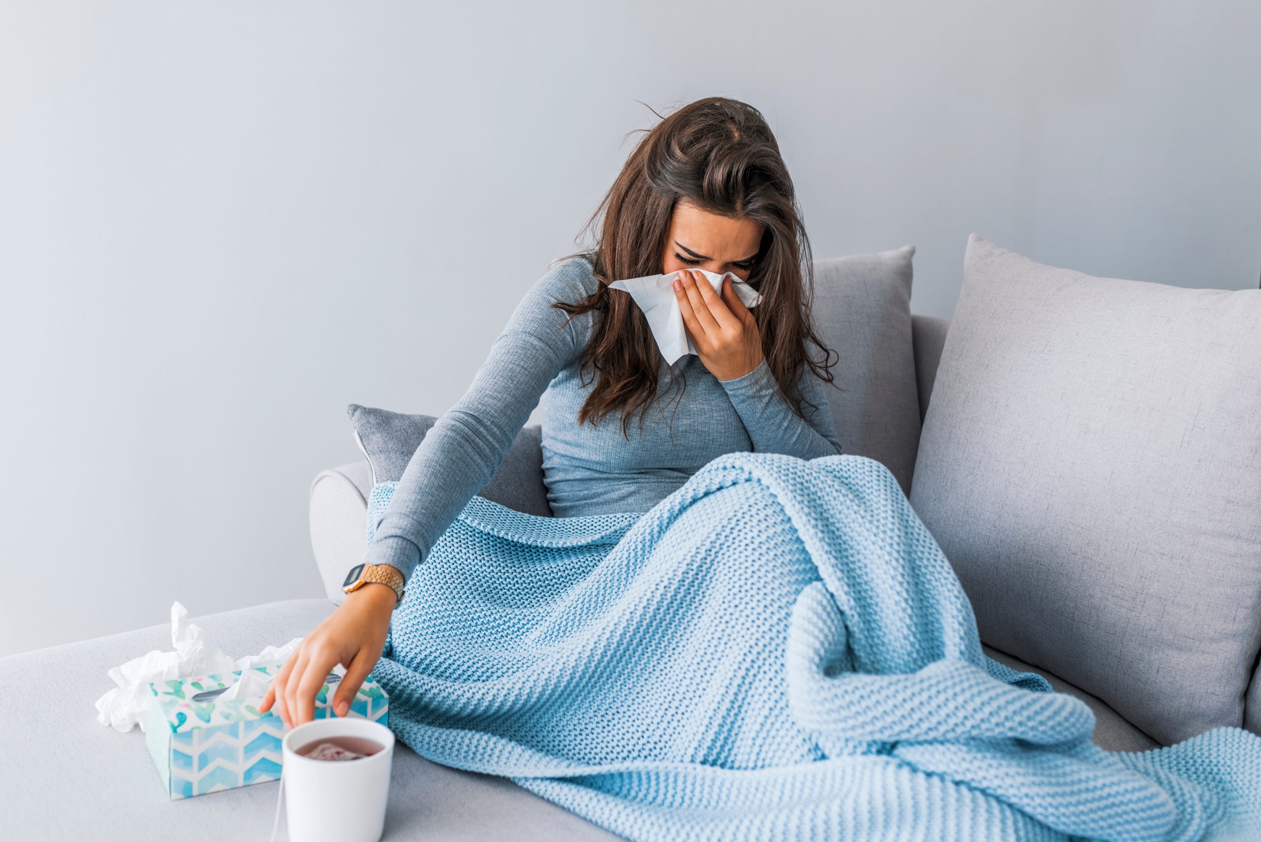 Sick woman with headache sitting under the blanket.