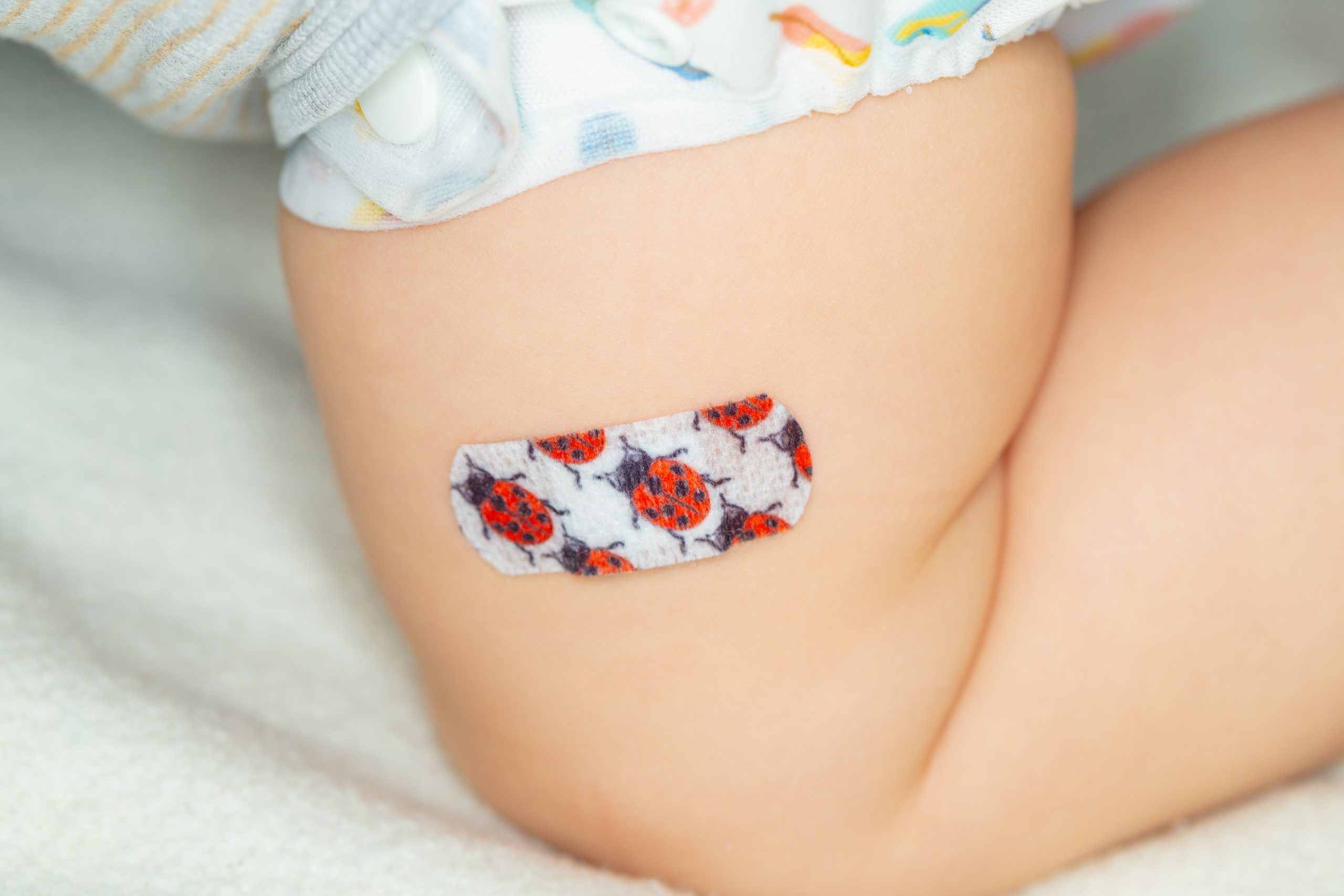 Colorful patch on the thigh of a young child after vaccine injection
