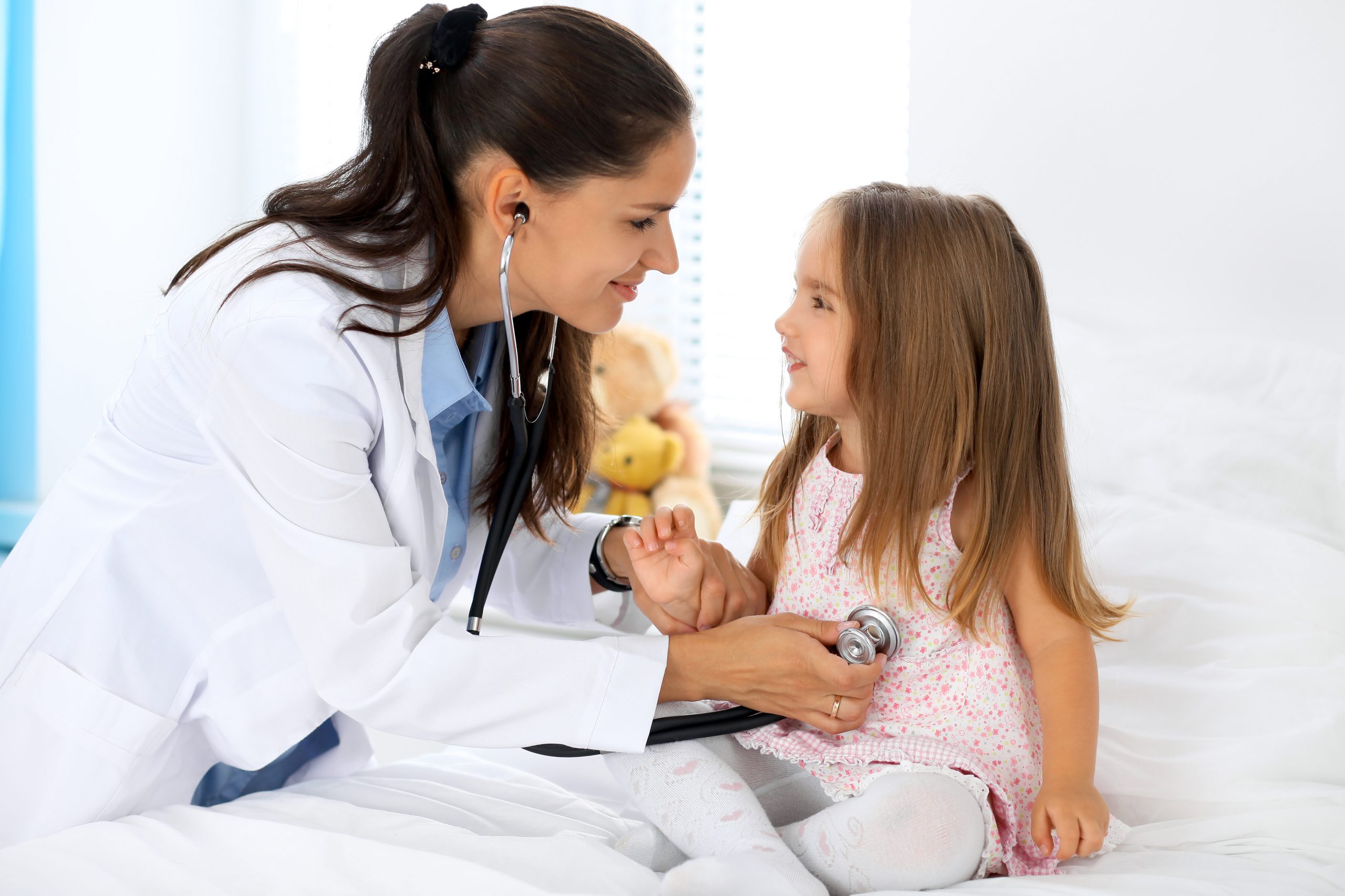 doctor using stethoscope on smiling child
