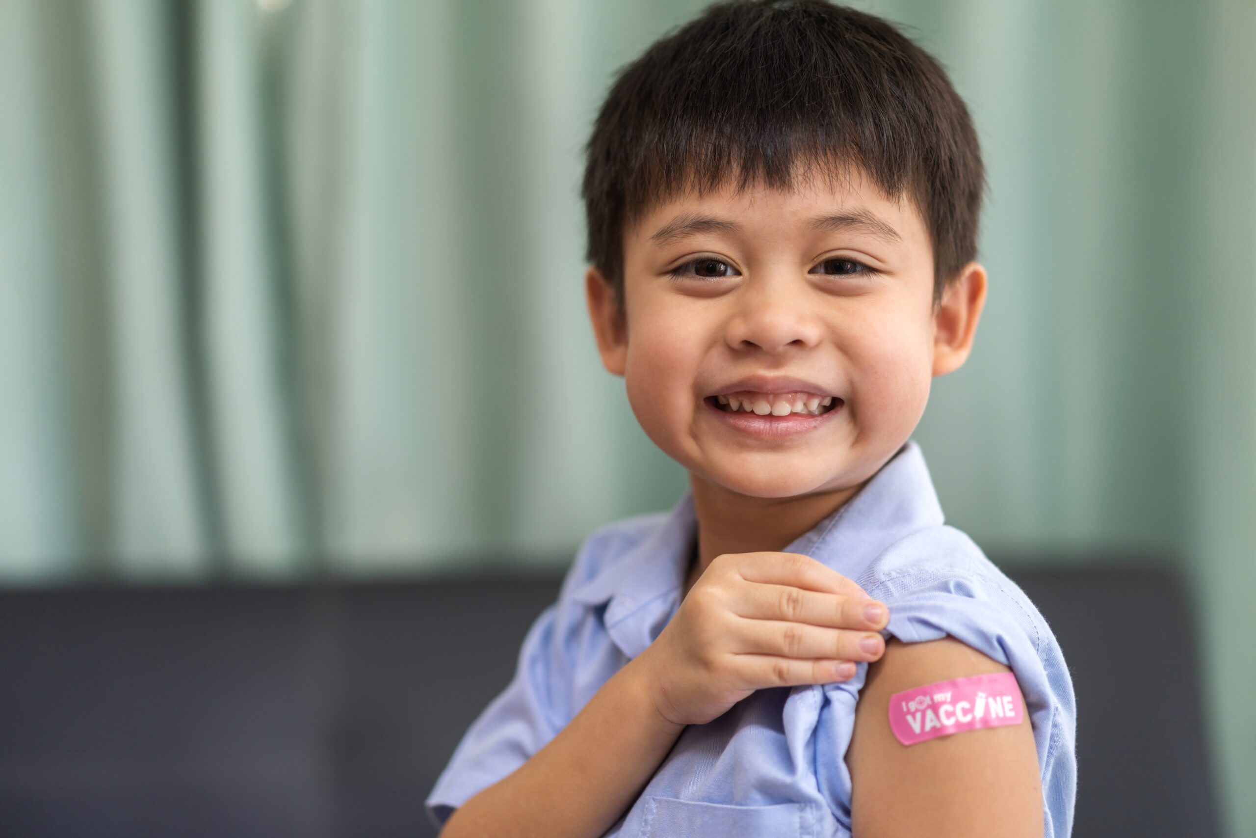 Young boy smiling and showing off bandage after a vaccine