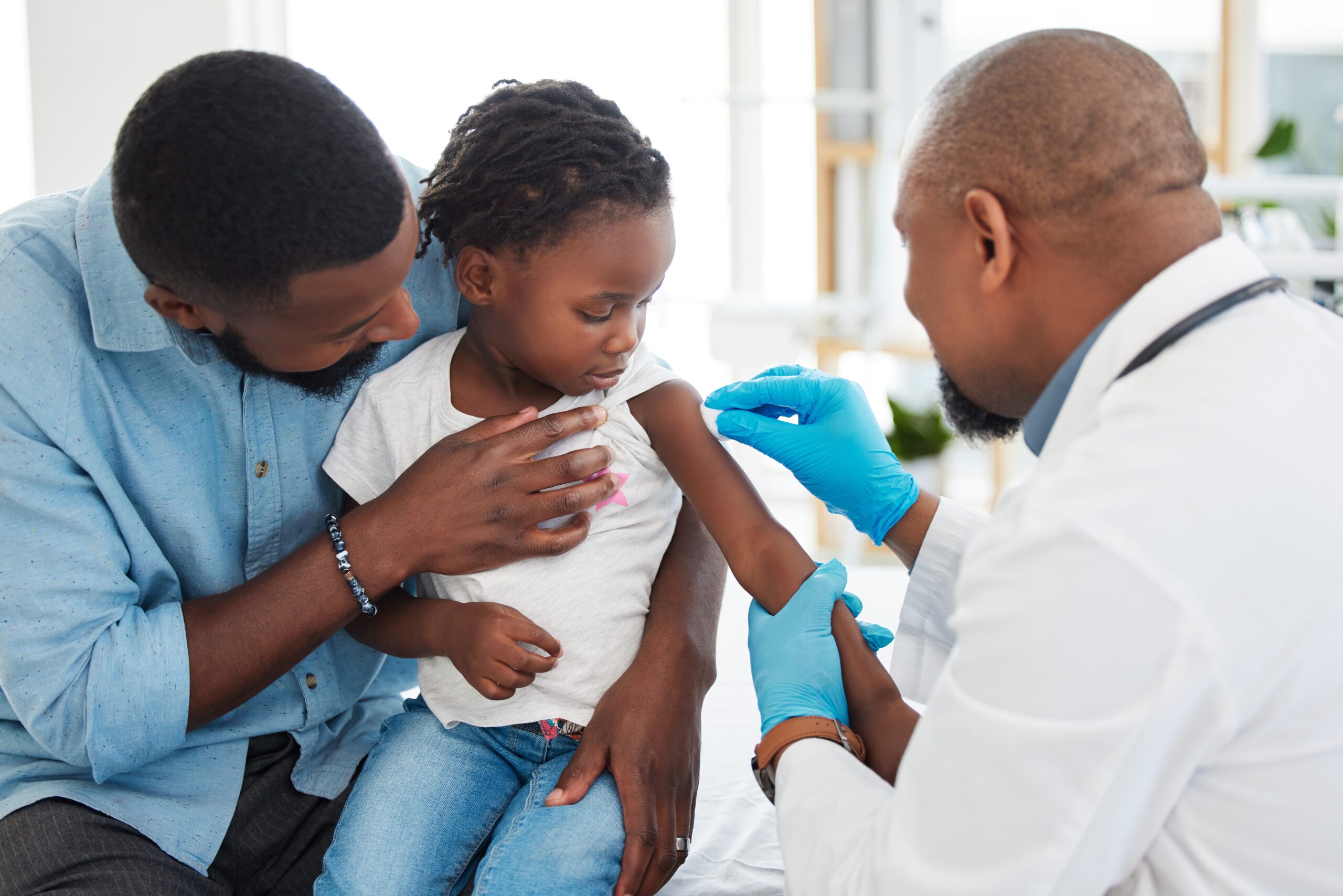 African American father holding his son, getting vaccine from doctor
