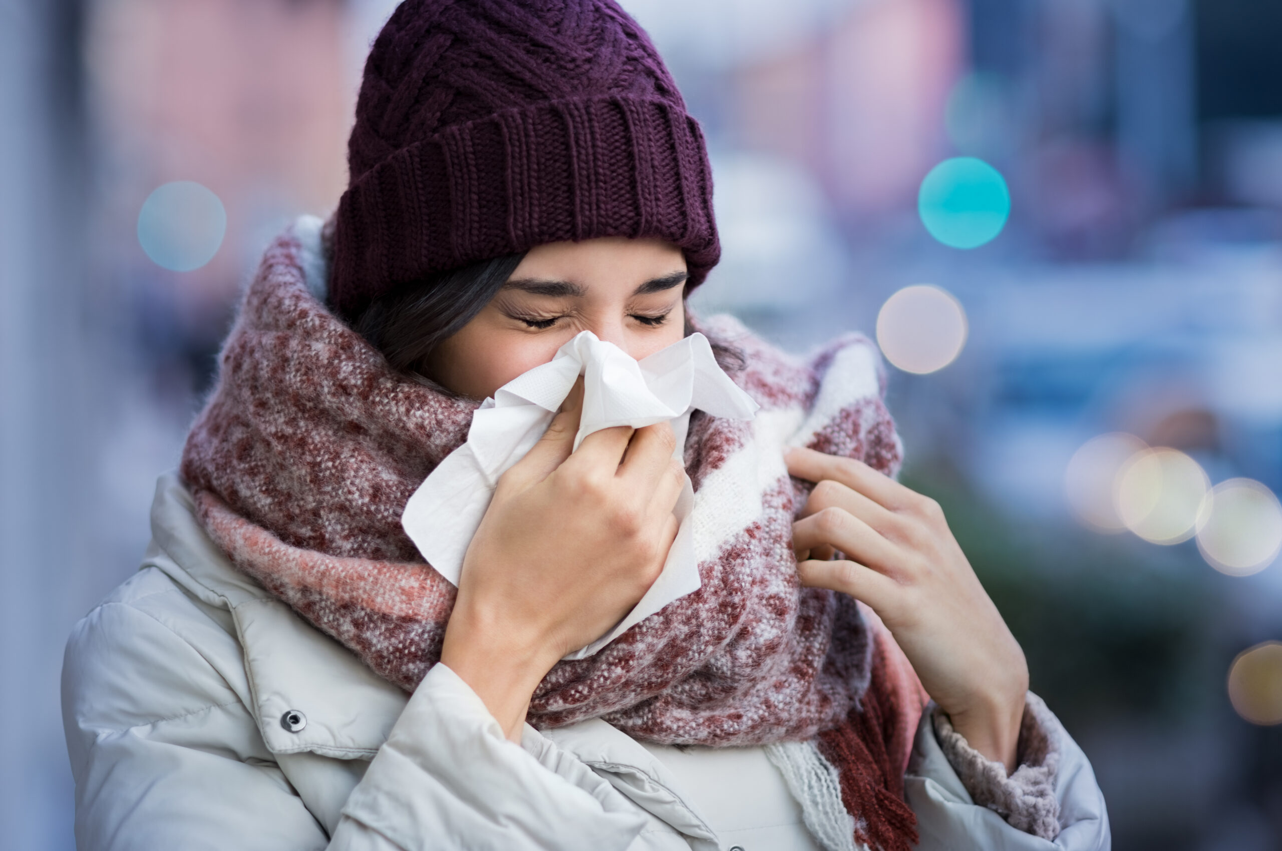 A woman blowing her nose outside in winter, flu season
