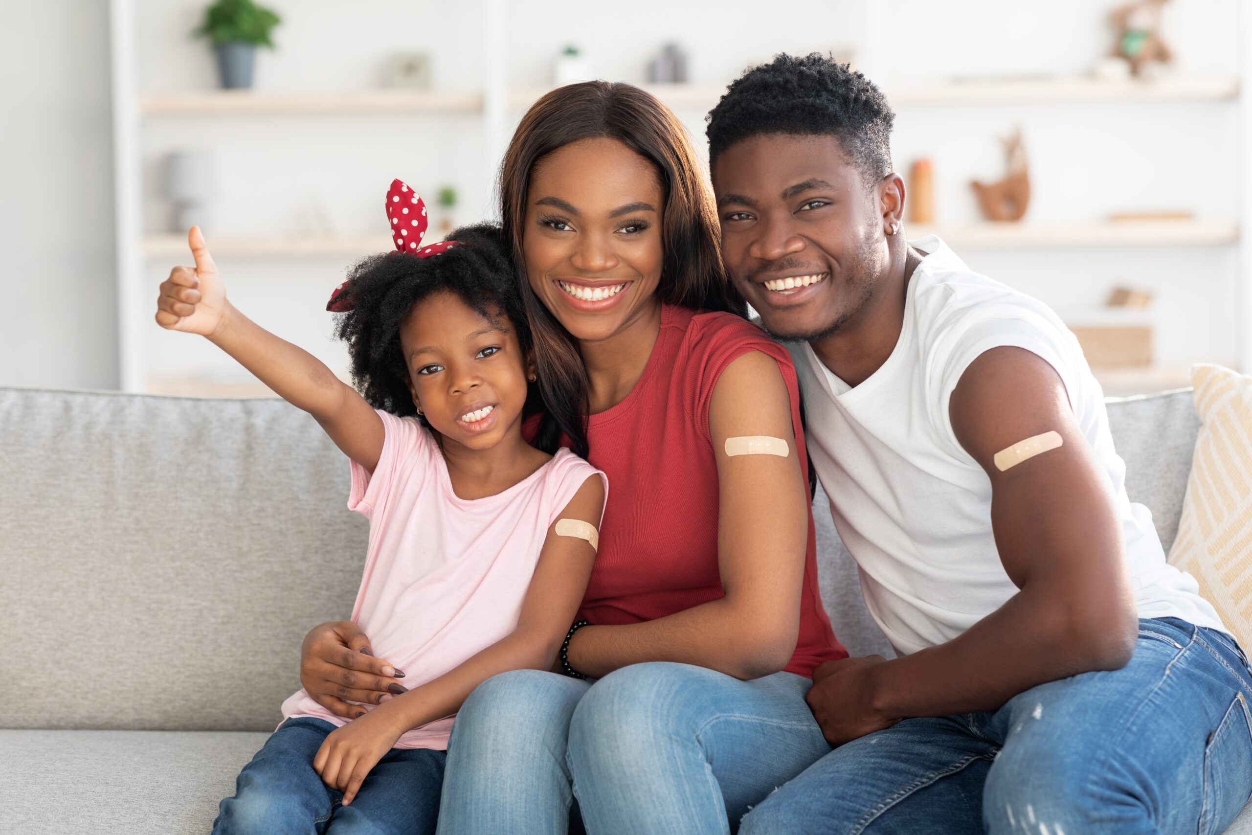 Family smiling after getting shots with bandaids on their arms