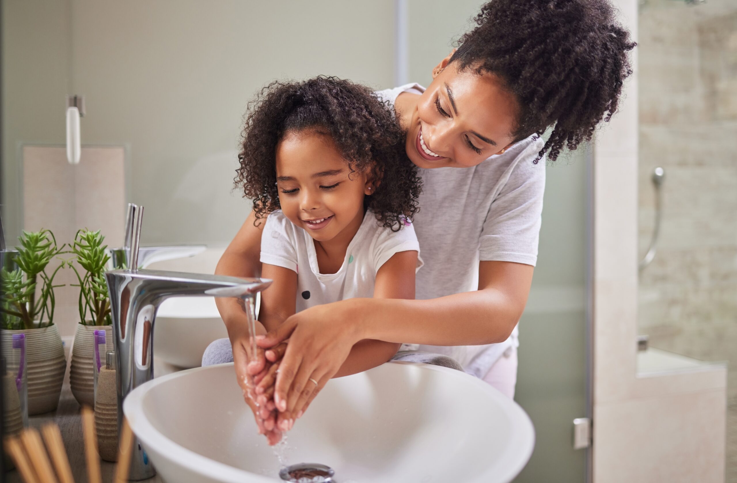 Mother helping daughter wash hands