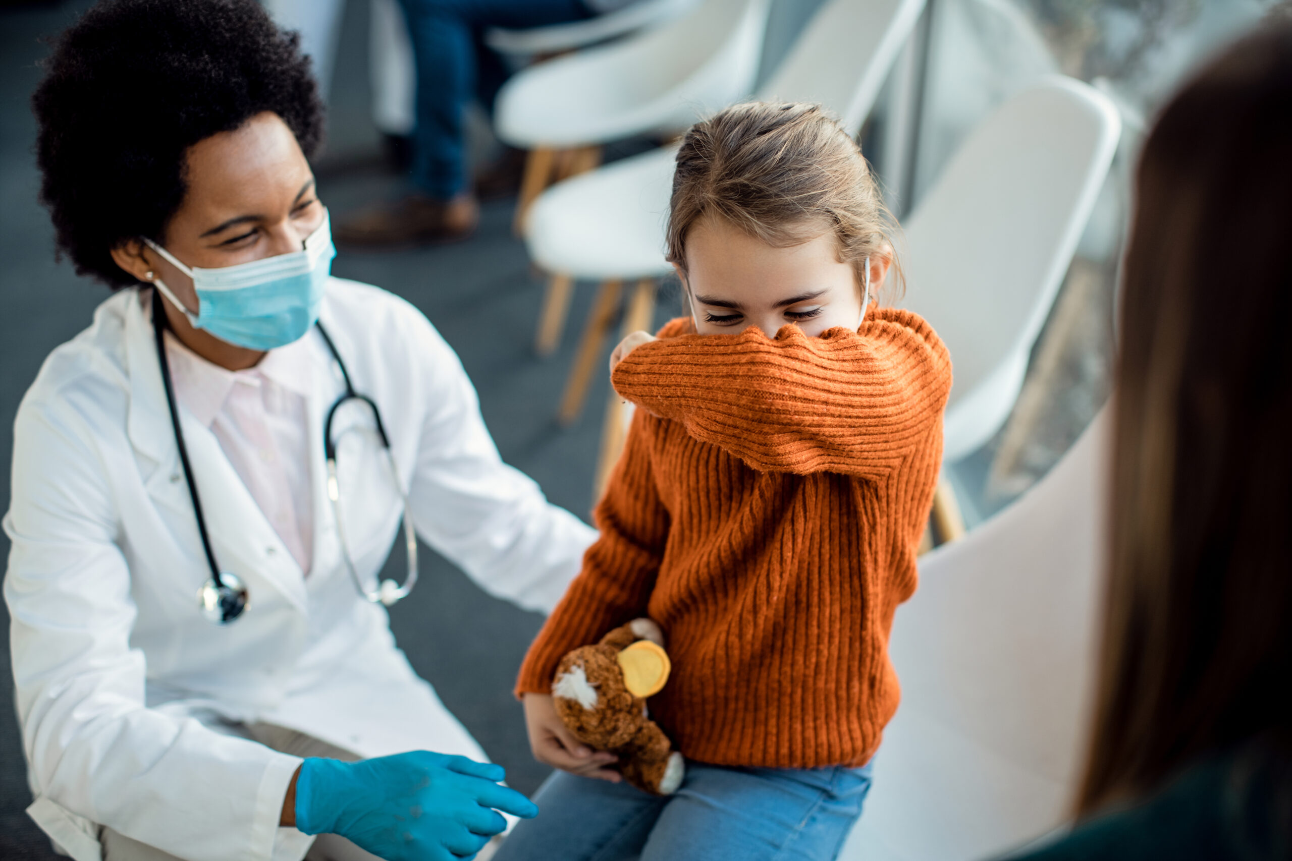 Child coughing into her elbow at the doctor's office