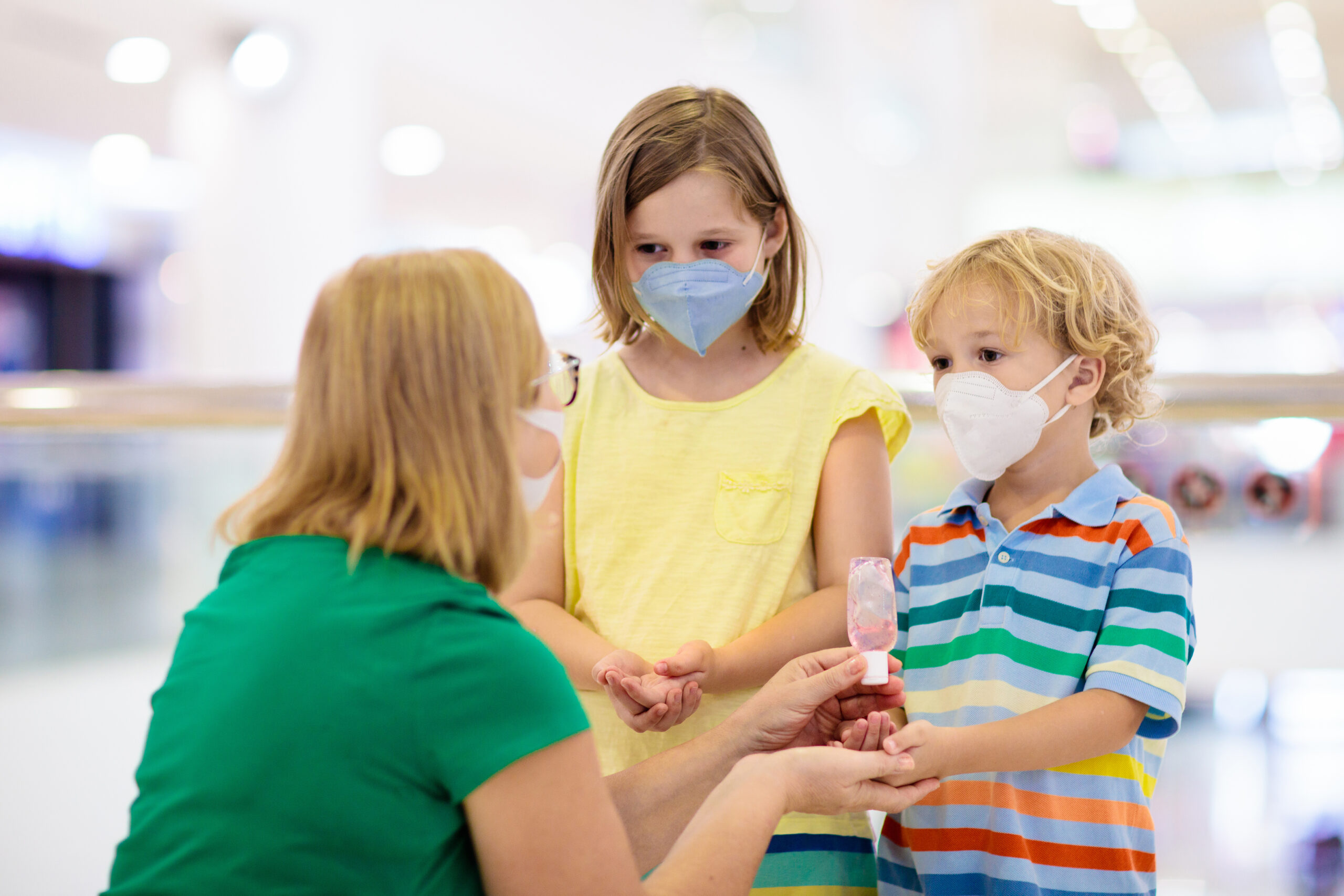 Children receiving hand sanitizer from adult