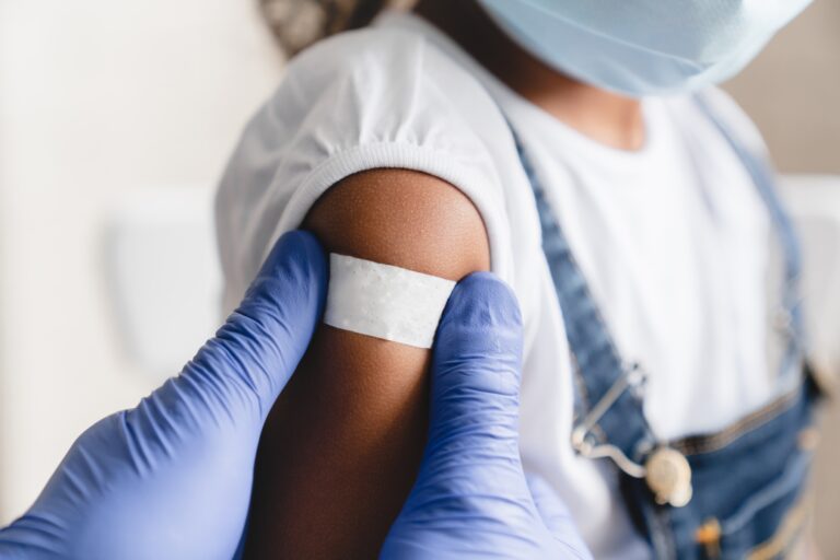 Doctor putting bandaid on child after a vaccine