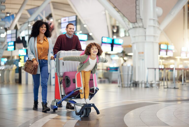 Family at the airport with daughter riding on luggage cart